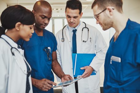 stock-photo-team-of-multiracial-doctors-at-hospital-discussing-a-patient-doctors-using-tablet-400845937